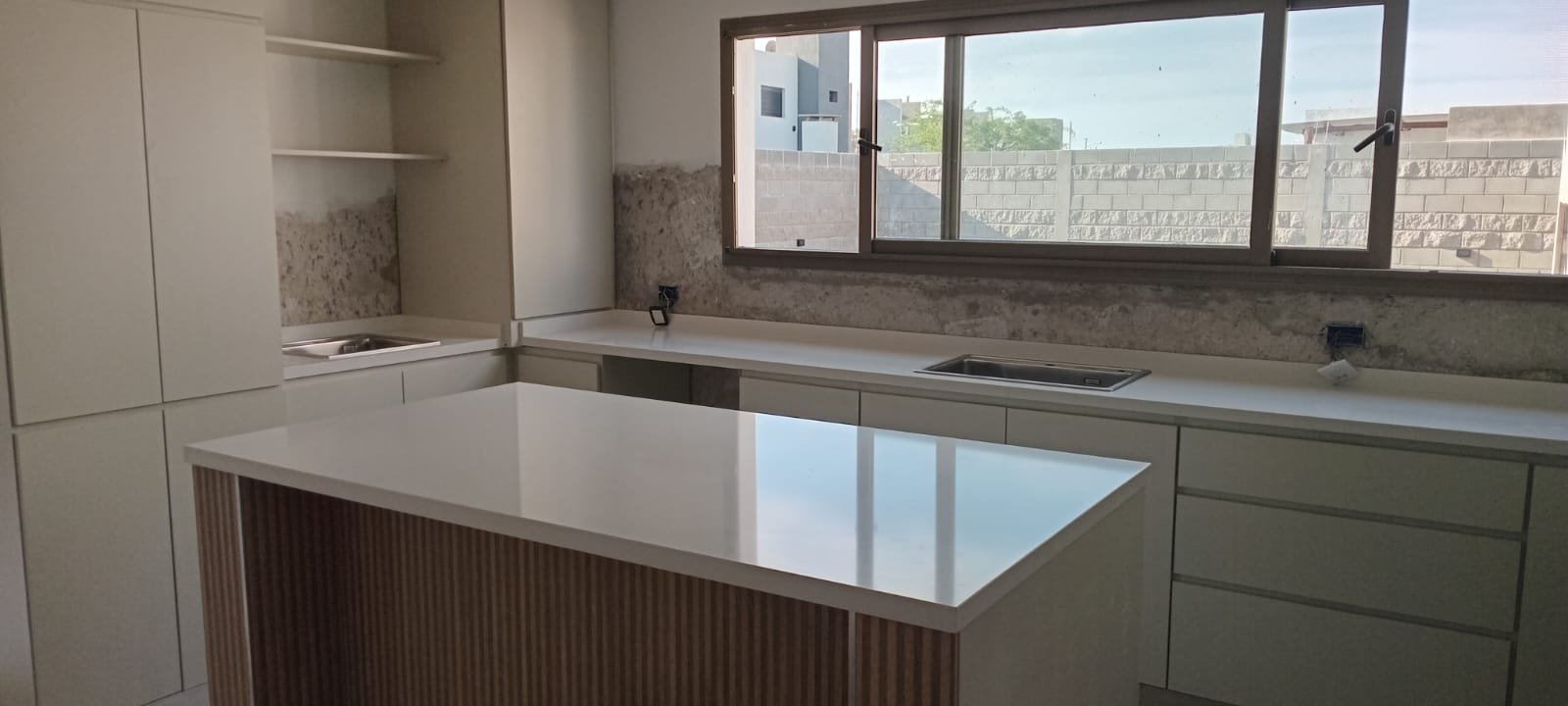 Cocina con isla de mármol blanco y mesada perimetral