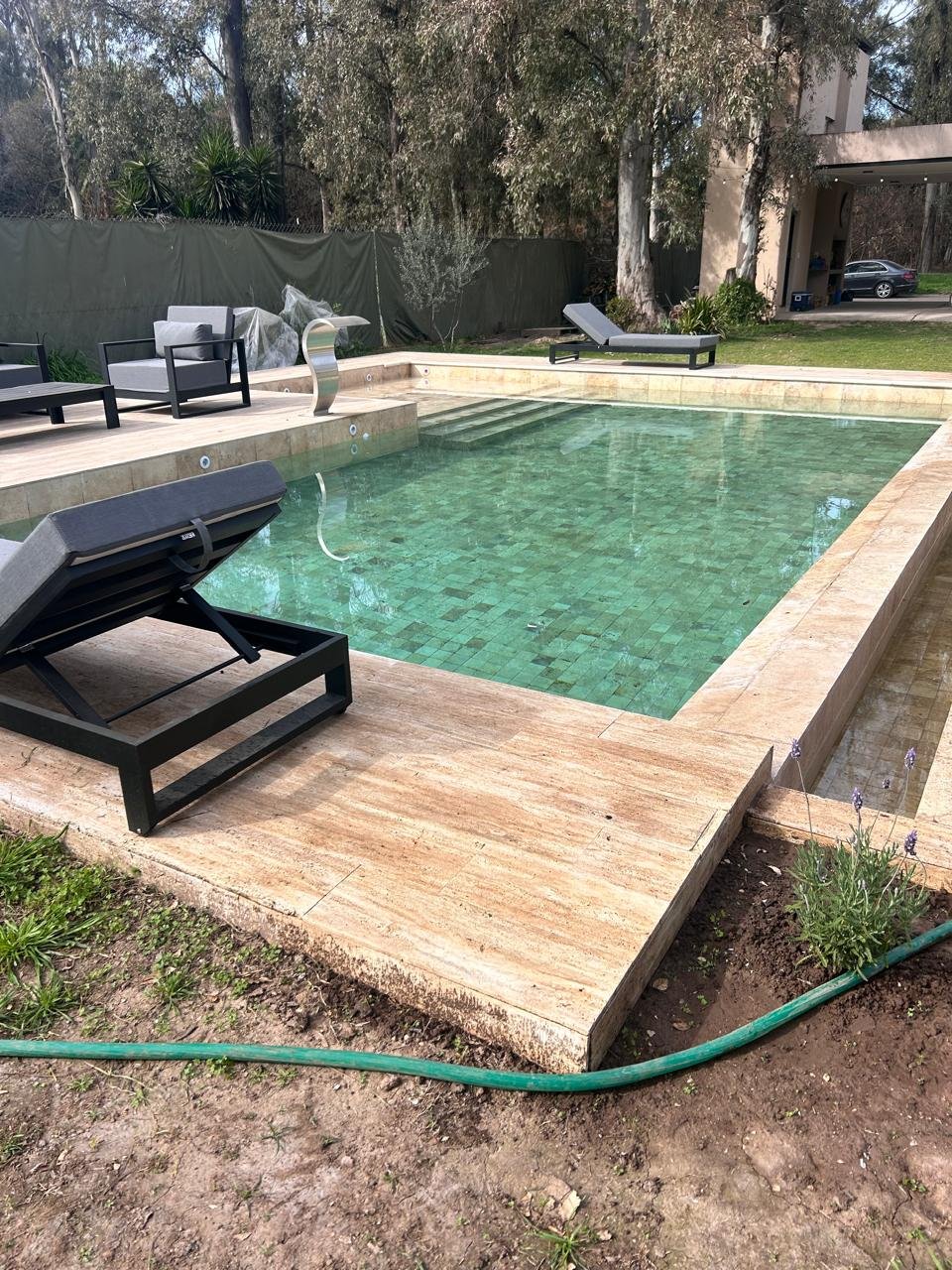 Piscina revestida con borde de piedra travertino